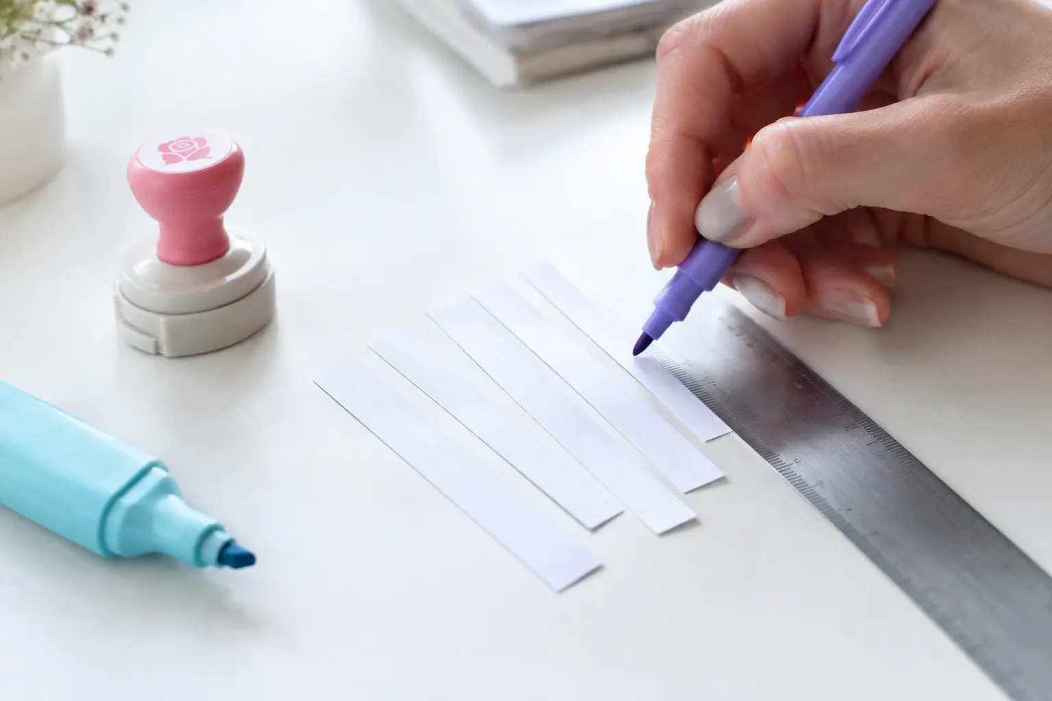 Bandes de papier alignées contre une règle et relues au stylo violet, comme des meta descriptions rédigées par l’IA puis validées